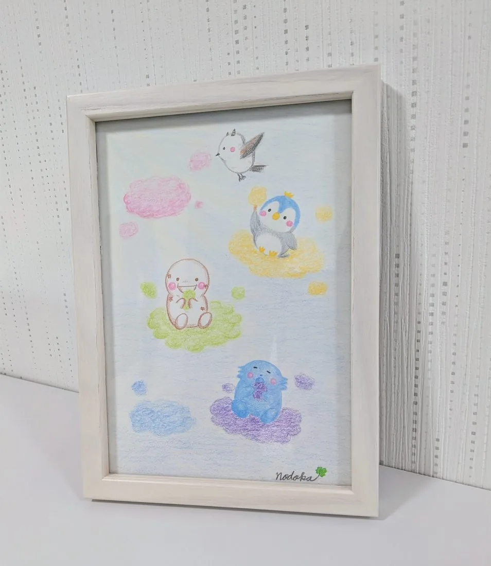 雲に乗ったふうふうとペンギンの絵を額に入れた様子